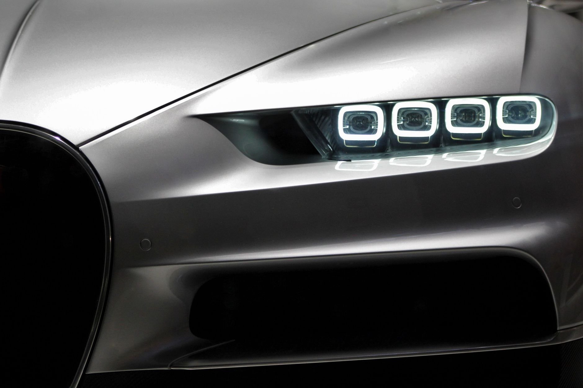 Close-up of luxury sports car headlight with sleek design and modern LED lights at night.